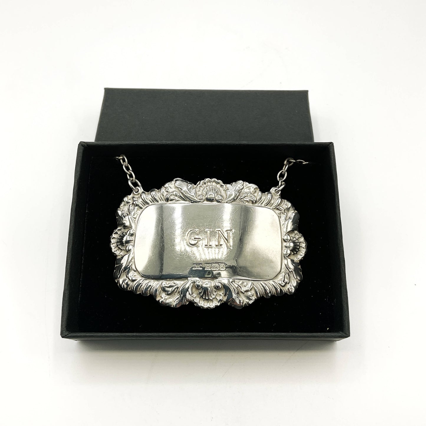 Silver label with GIN engraving in a black box on a white background