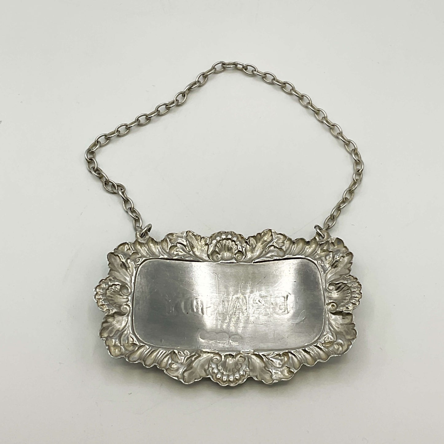 Silver decanter label with chain on a white background