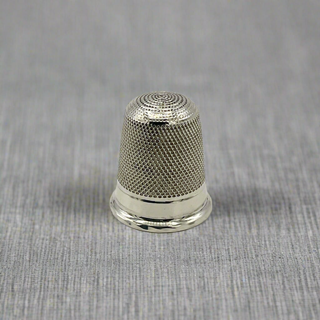Silver thimble on a light background