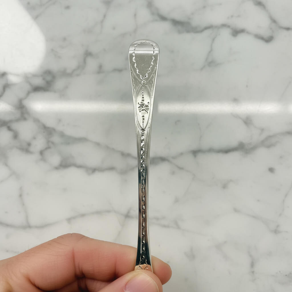 Silver spoon held by a hand against a marble background