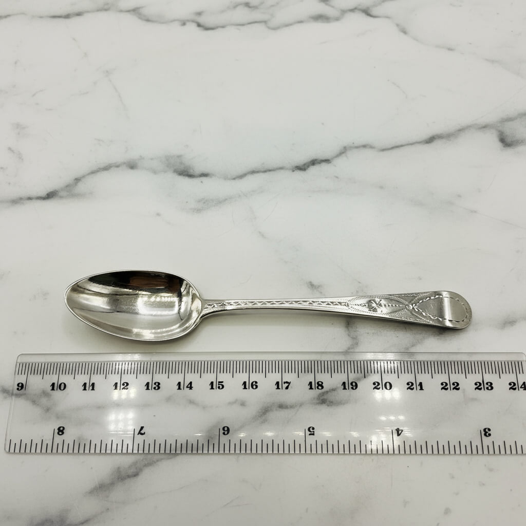 Silver spoon on a marble surface with a ruler for scale