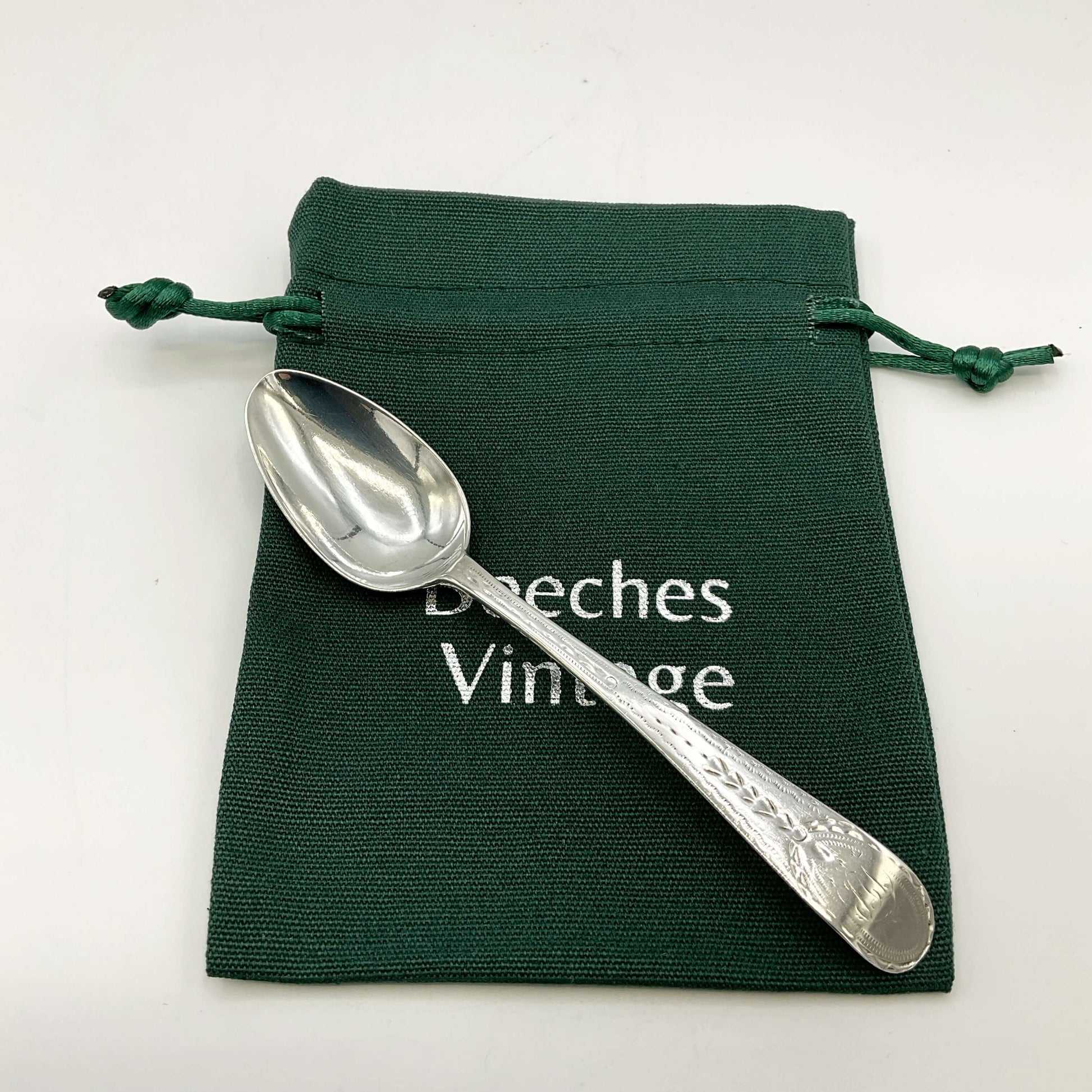 Silver spoon on a green drawstring bag with 'Beeches Vintage' branding.