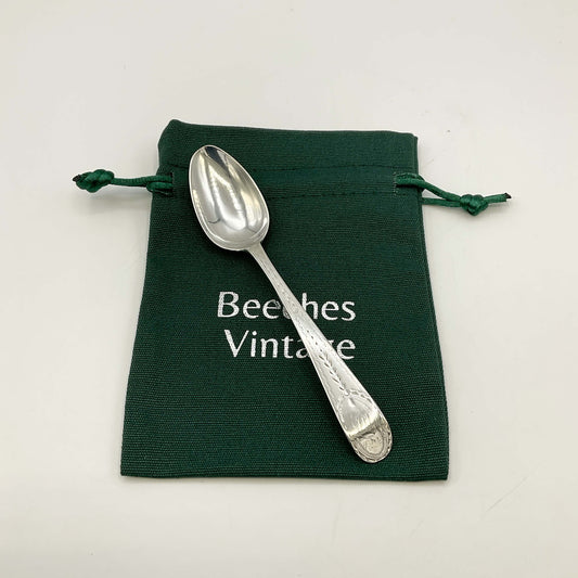 Silver spoon on a green drawstring bag with 'Beeches Vintage' text.
