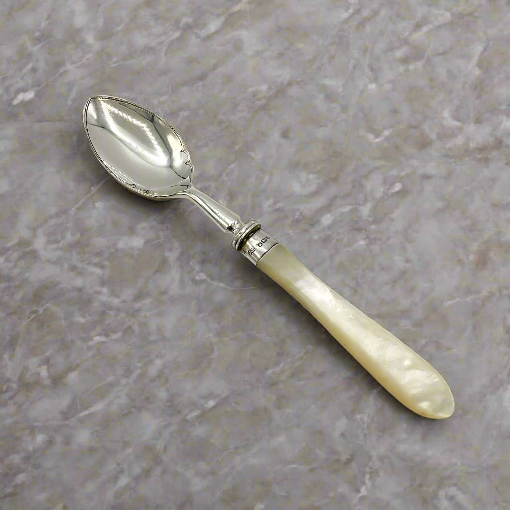 Silver spoon with a pearl handle on a light grey worktop