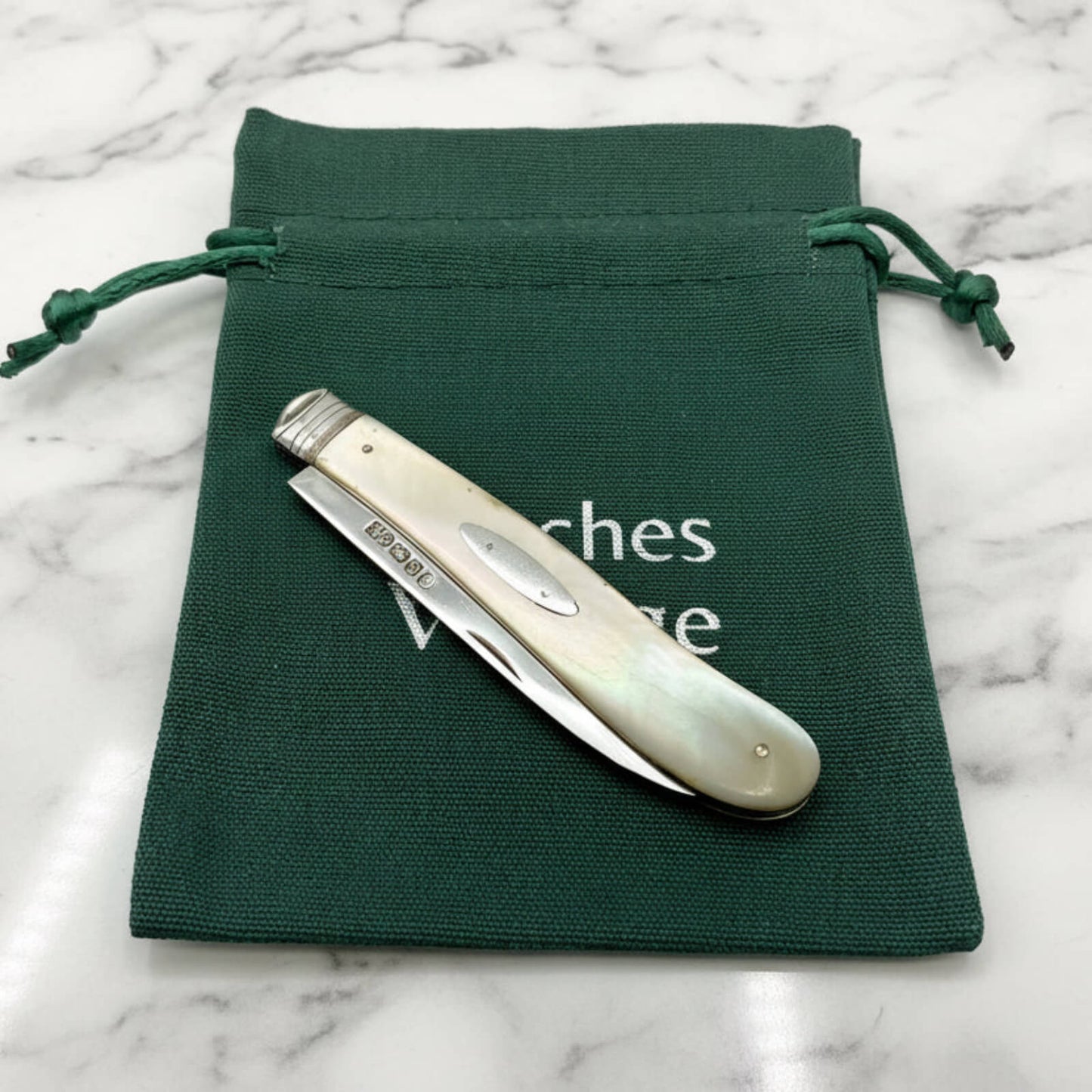 Large Antique Sterling Silver Fruit Knife on green bag on marble surface