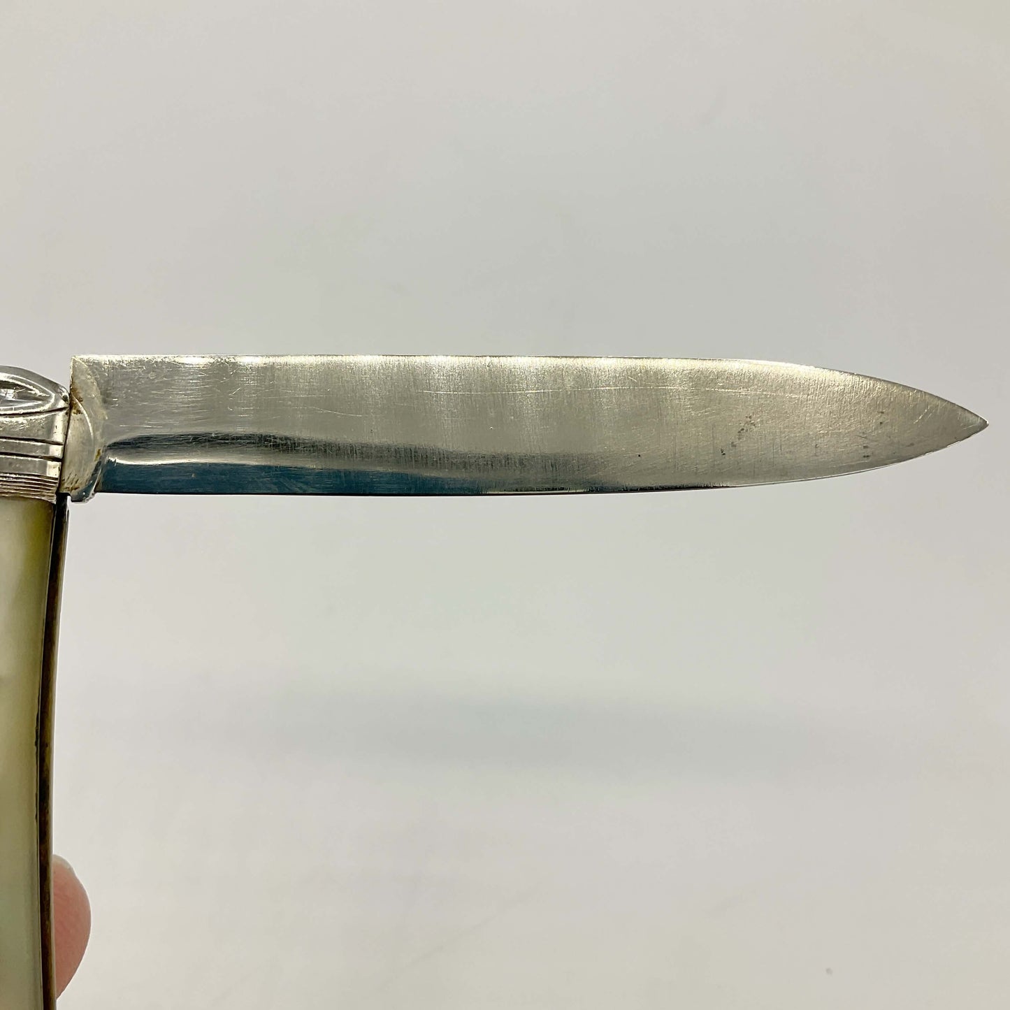 Close-up of a silver knife blade on a light gray background