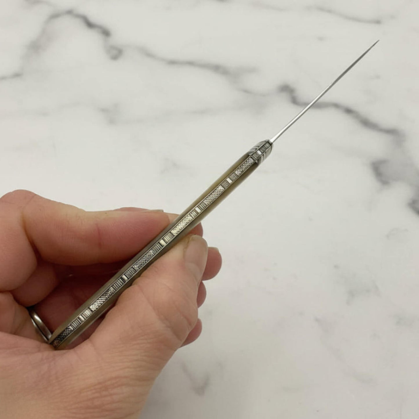 Large Antique Sterling Silver Fruit Knife back held in fingers with a marble background