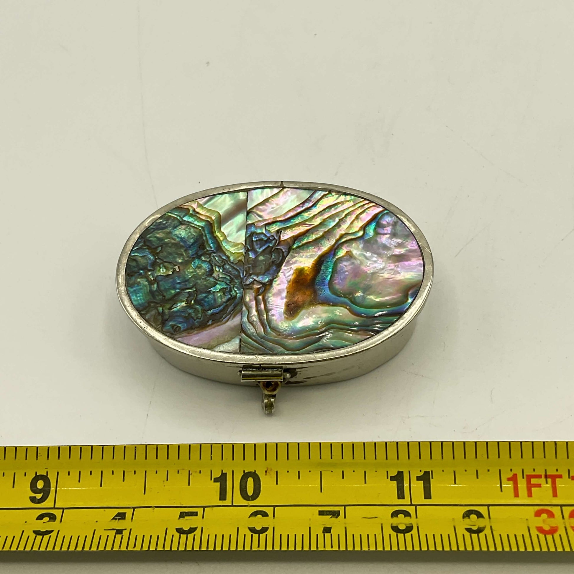 Mexican Abalone Shell Pill Box next to a tape measure for scale on a white surface