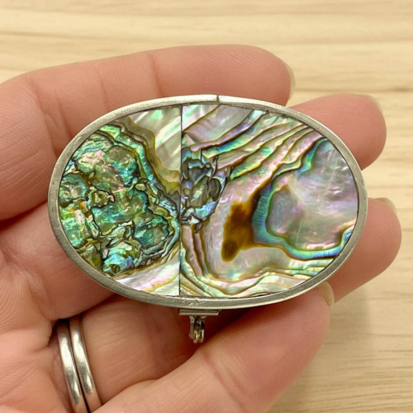 Mexican Abalone Shell Pill Box held in a hand with wood background