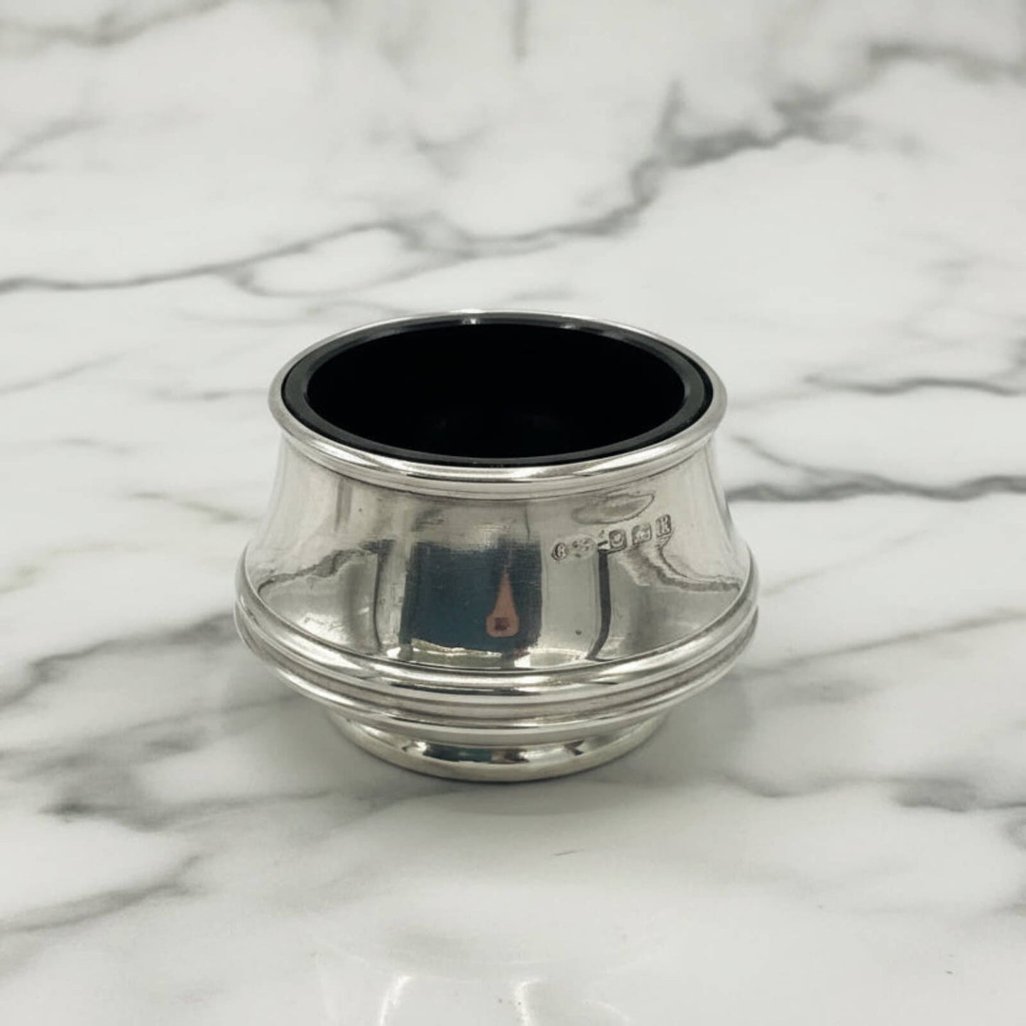 Silver salt with blue liner on a marble surface