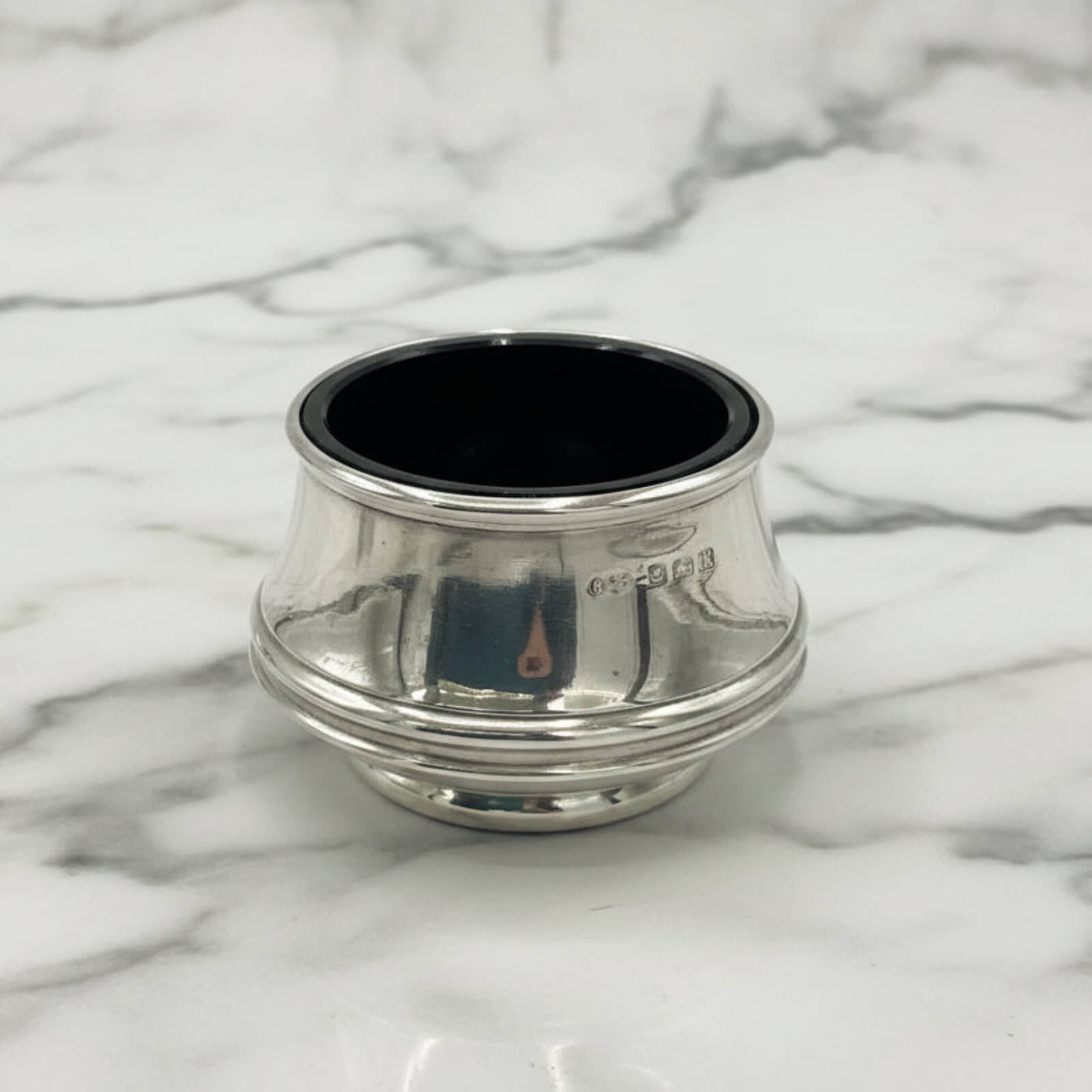 Silver salt with blue liner on a marble surface