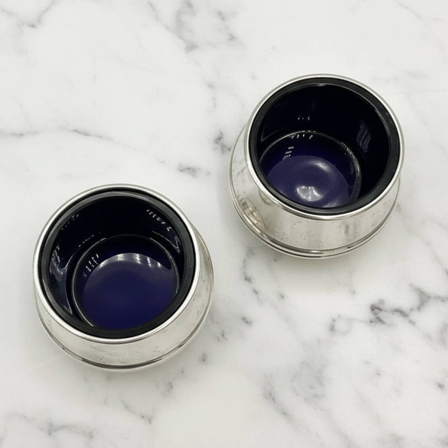 Two salts with blue interior on a marble surface
