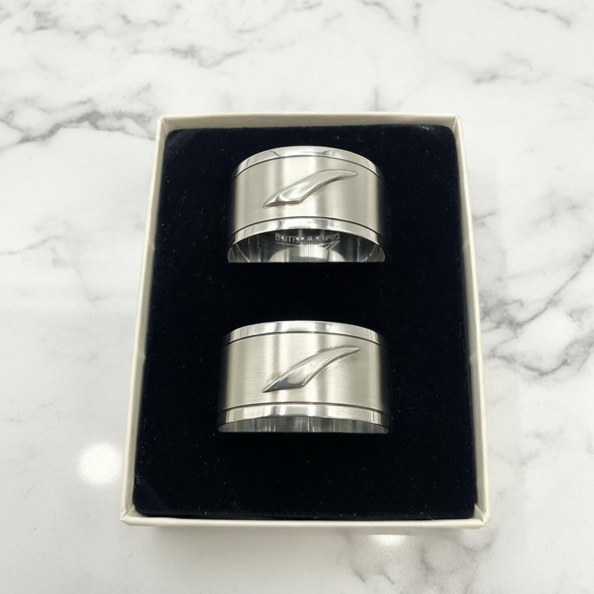Pair of Concorde Sterling Silver Napkin Rings with a stylized wave design, presented in a black velvet-lined gift box on a white background.