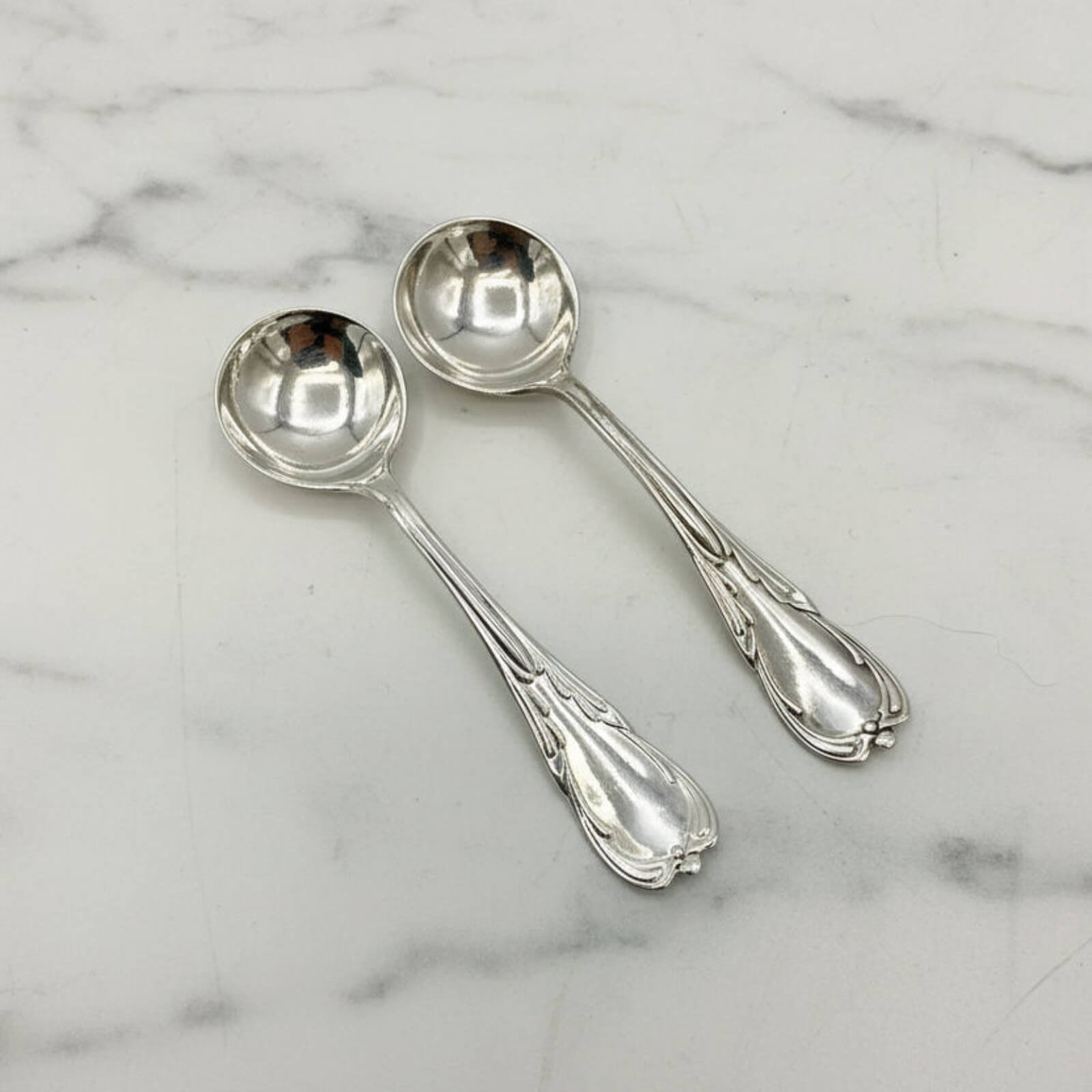 Two silver spoons on a marble surface