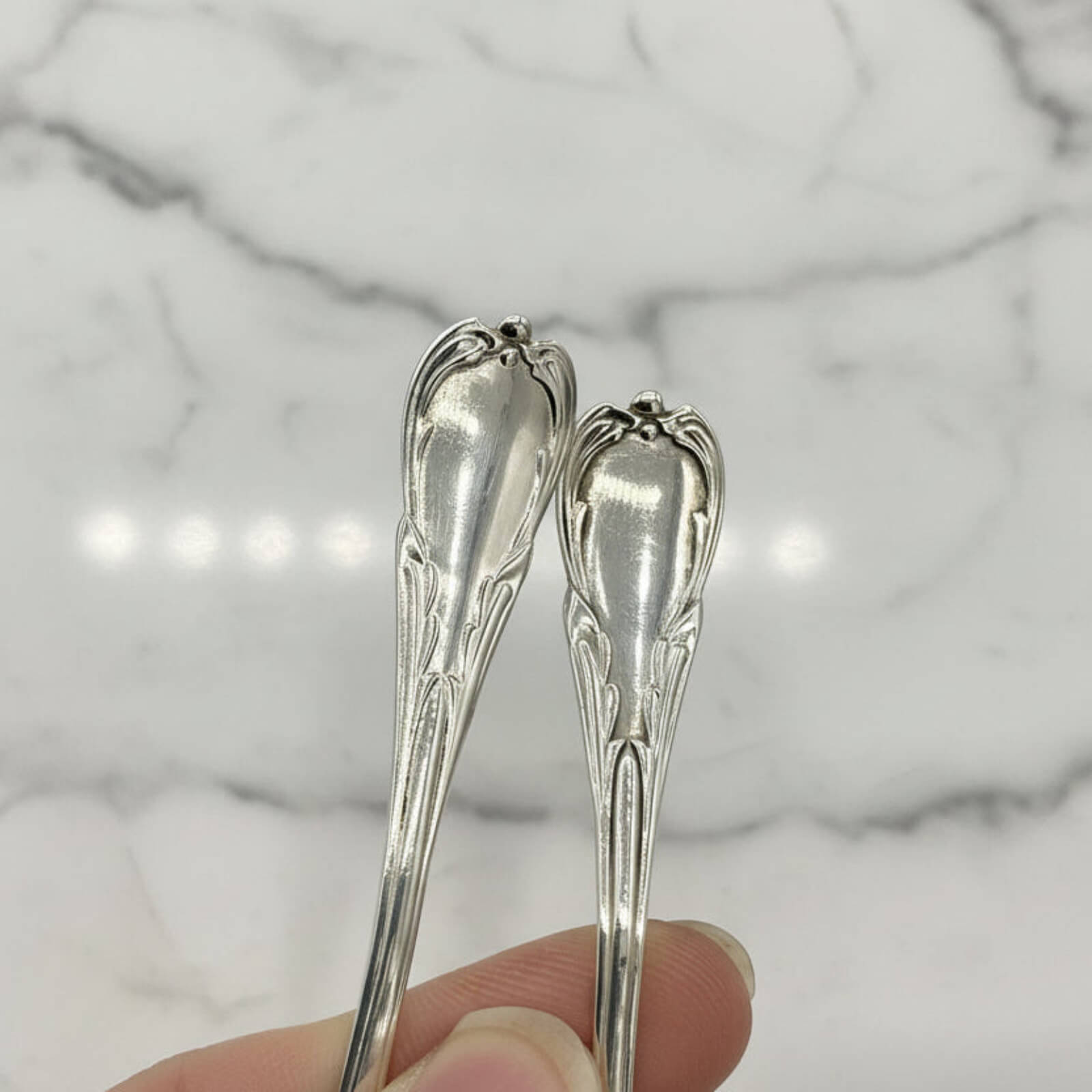 Two silver spoons held against a marble background