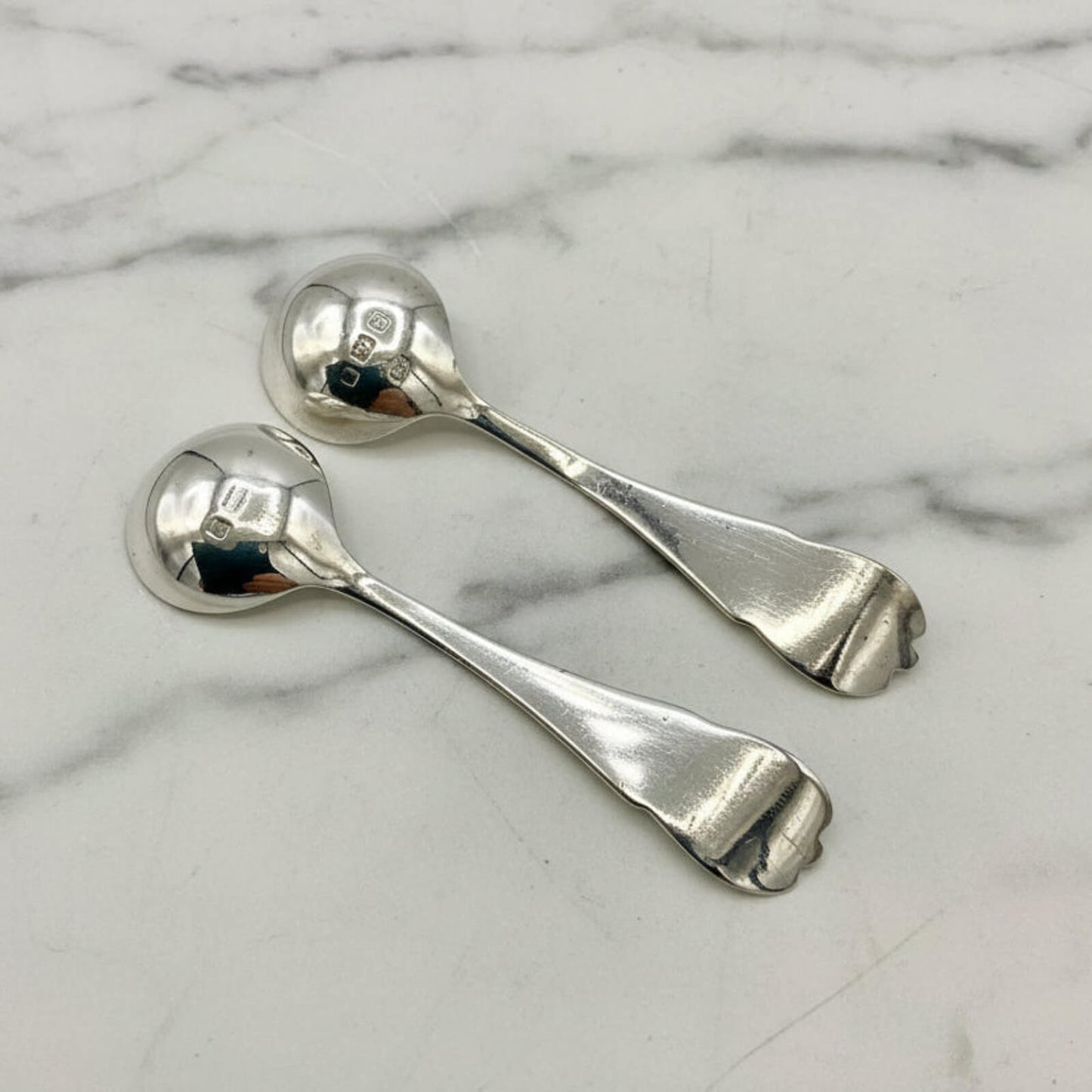 Two silver spoons on a marble surface