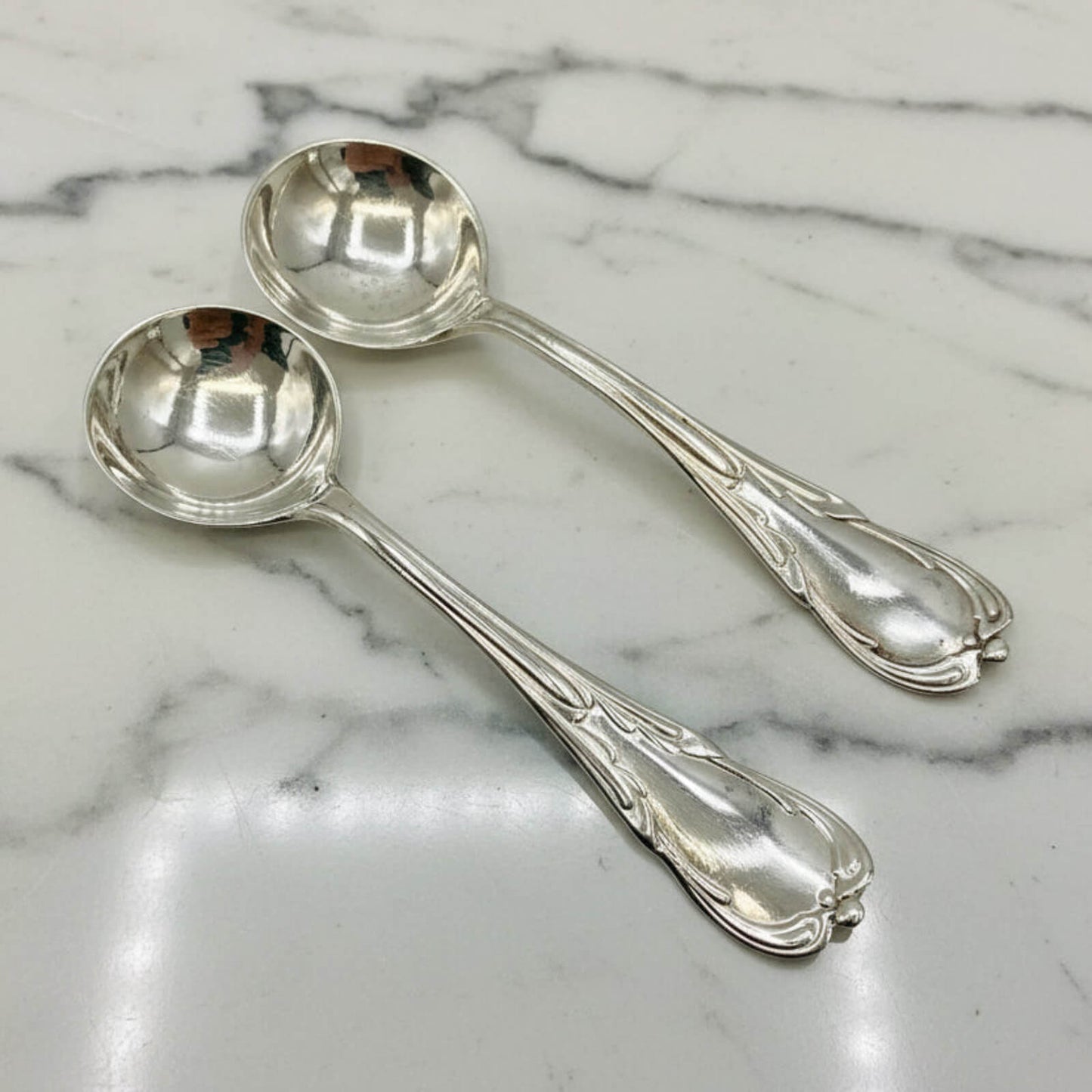 Two silver spoons on a marble surface