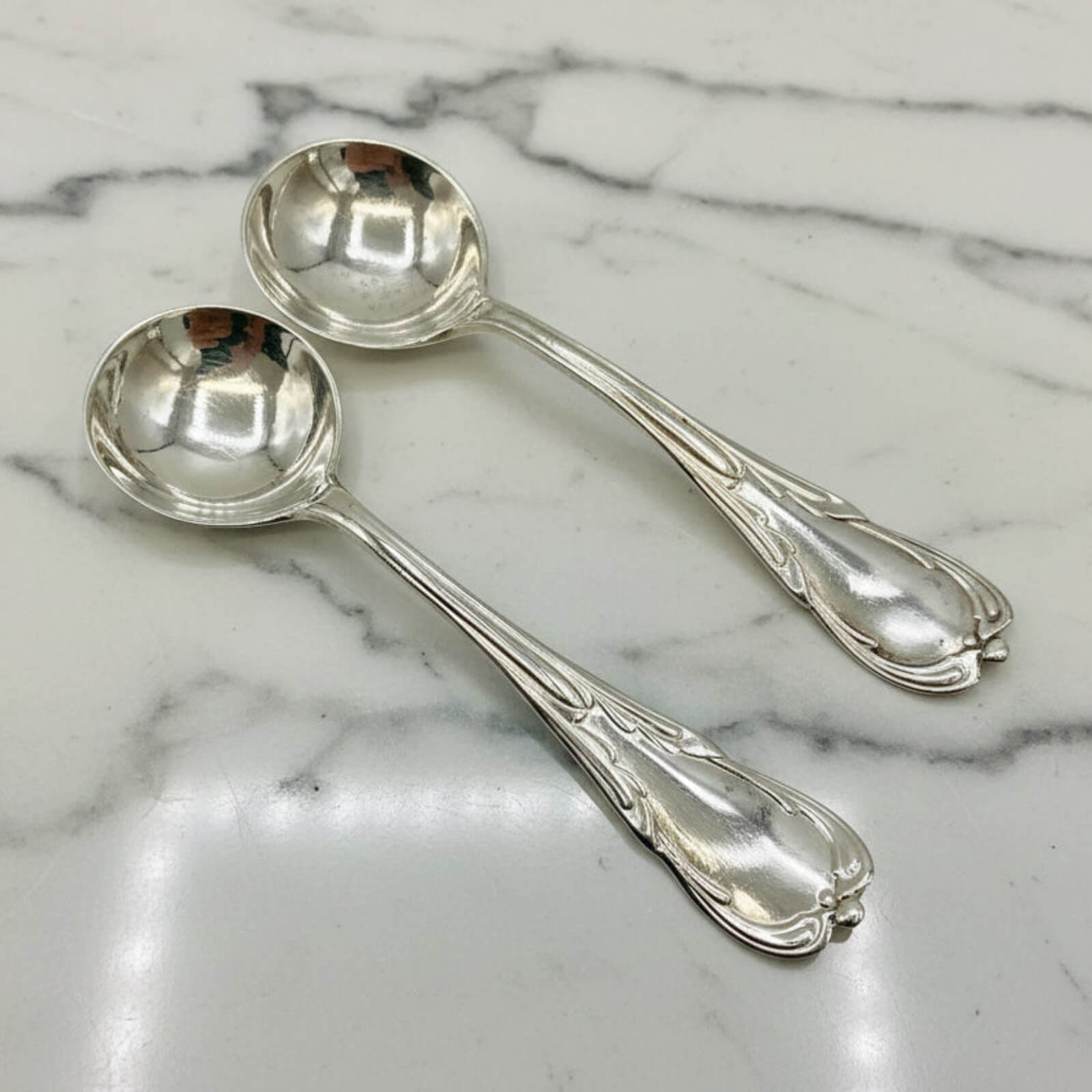 Two silver spoons on a marble surface