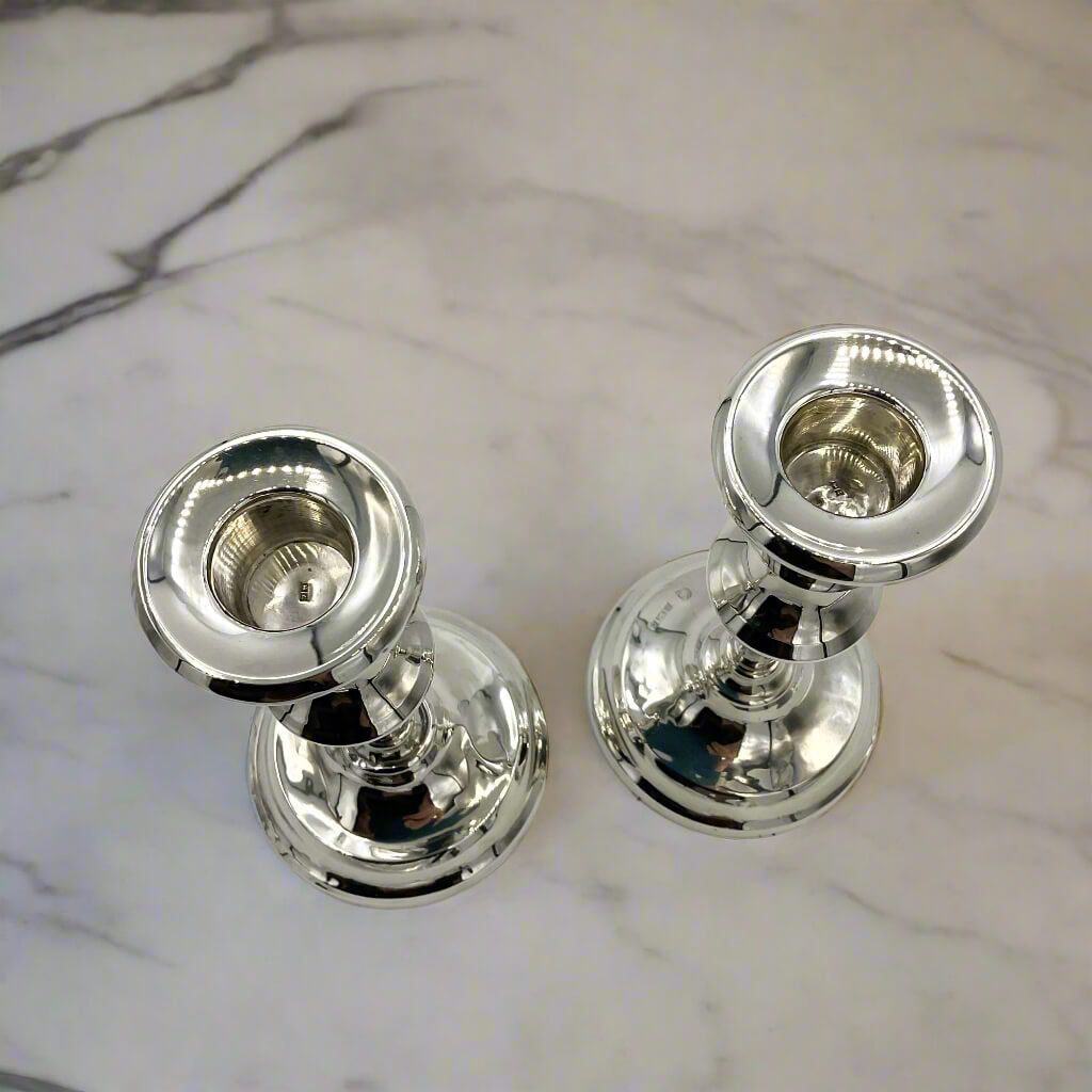 Two silver candle holders on a marble surface