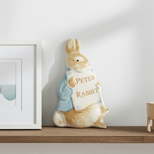 Decorative plaque shaped like a rabbit with 'Peter Rabbit' text on a shelf.