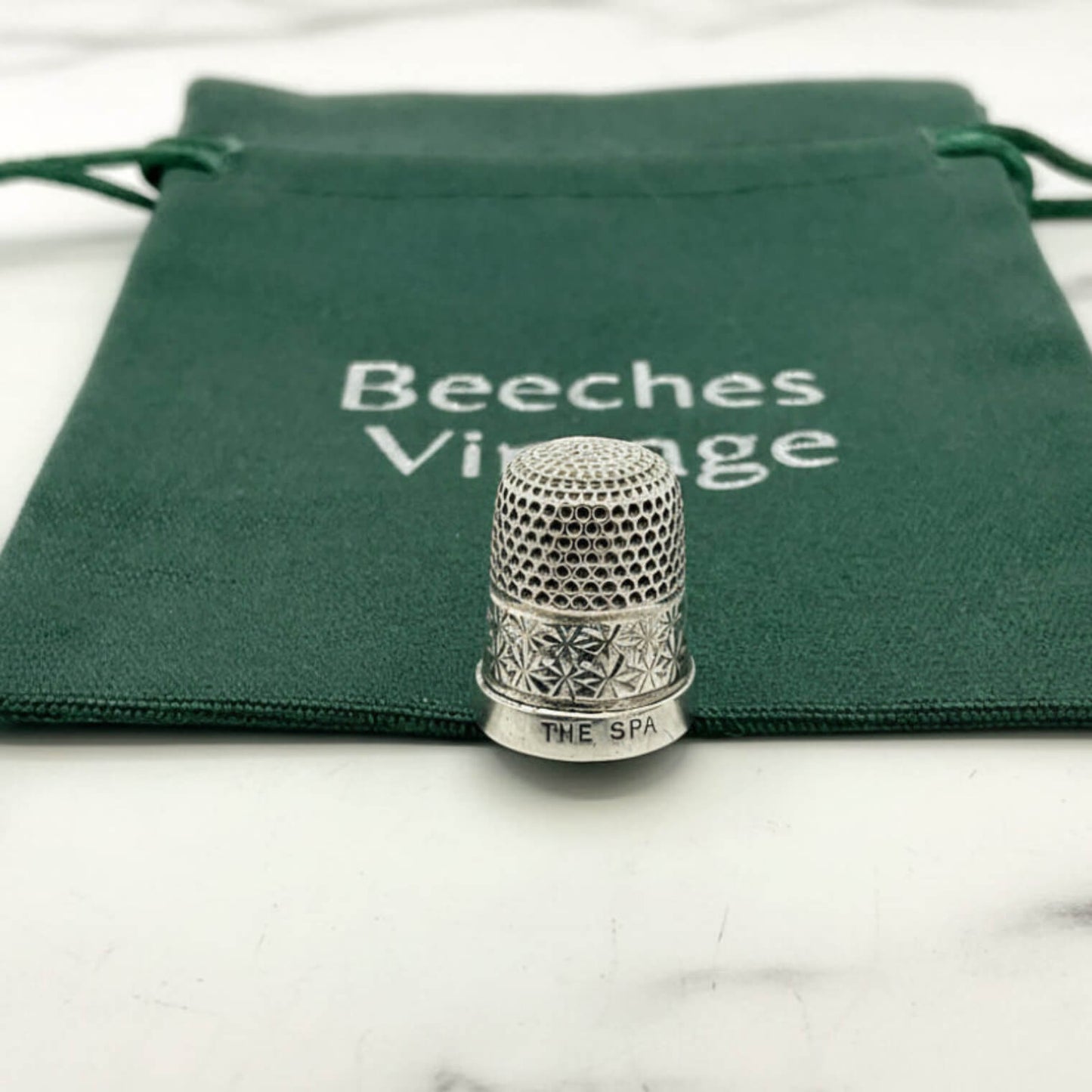 Silver thimble on a green drawstring bag with 'Beeches Vintage' branding.