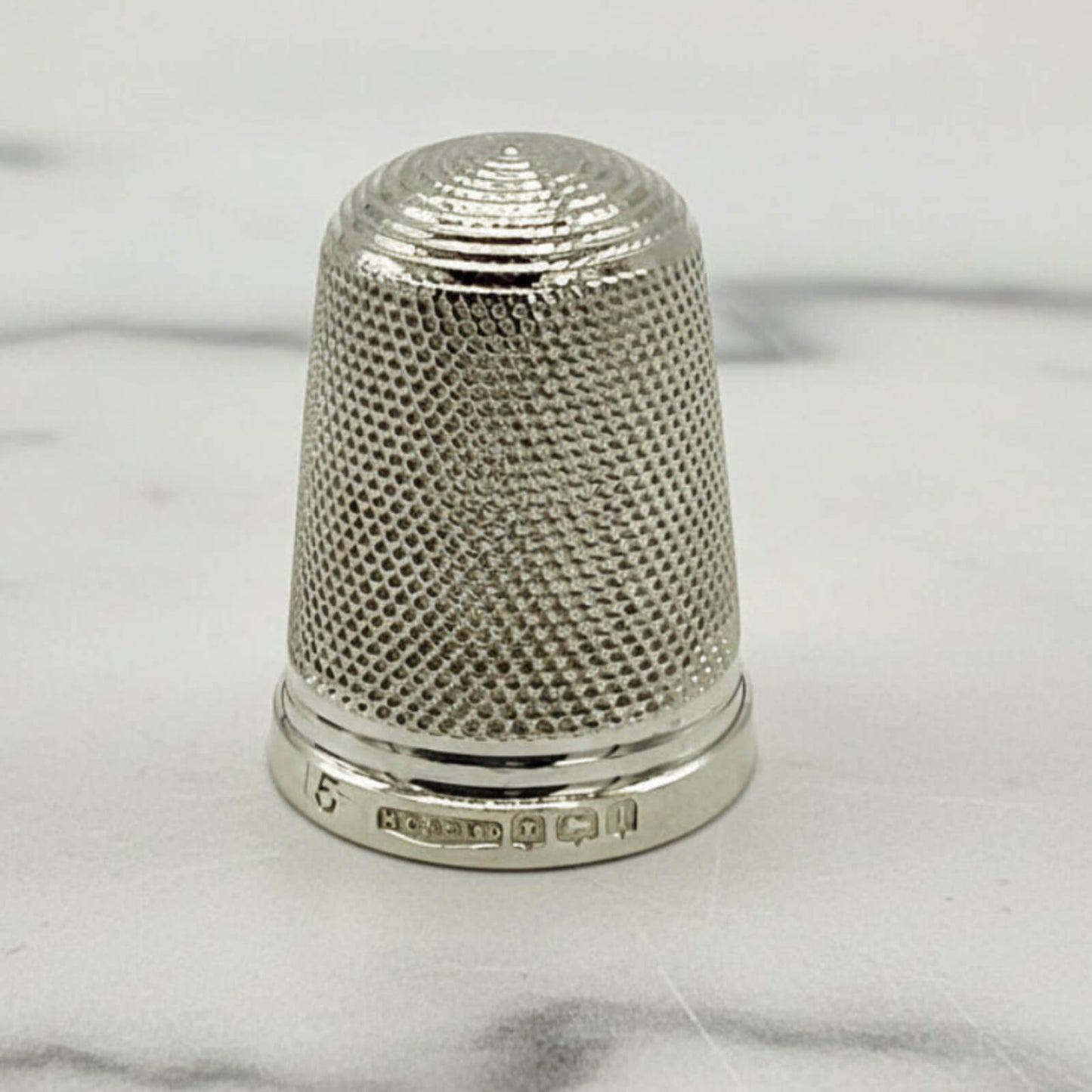 Silver thimble on a marble surface