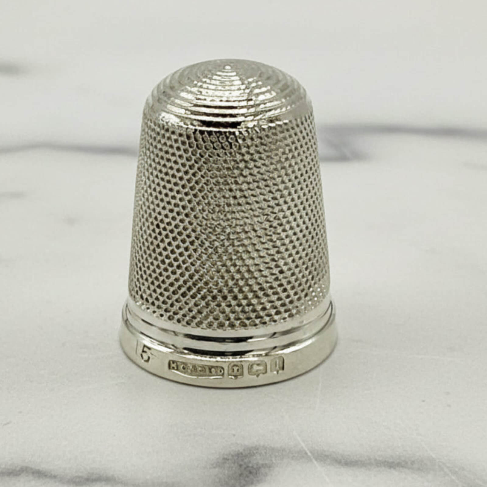 Silver thimble on a marble surface