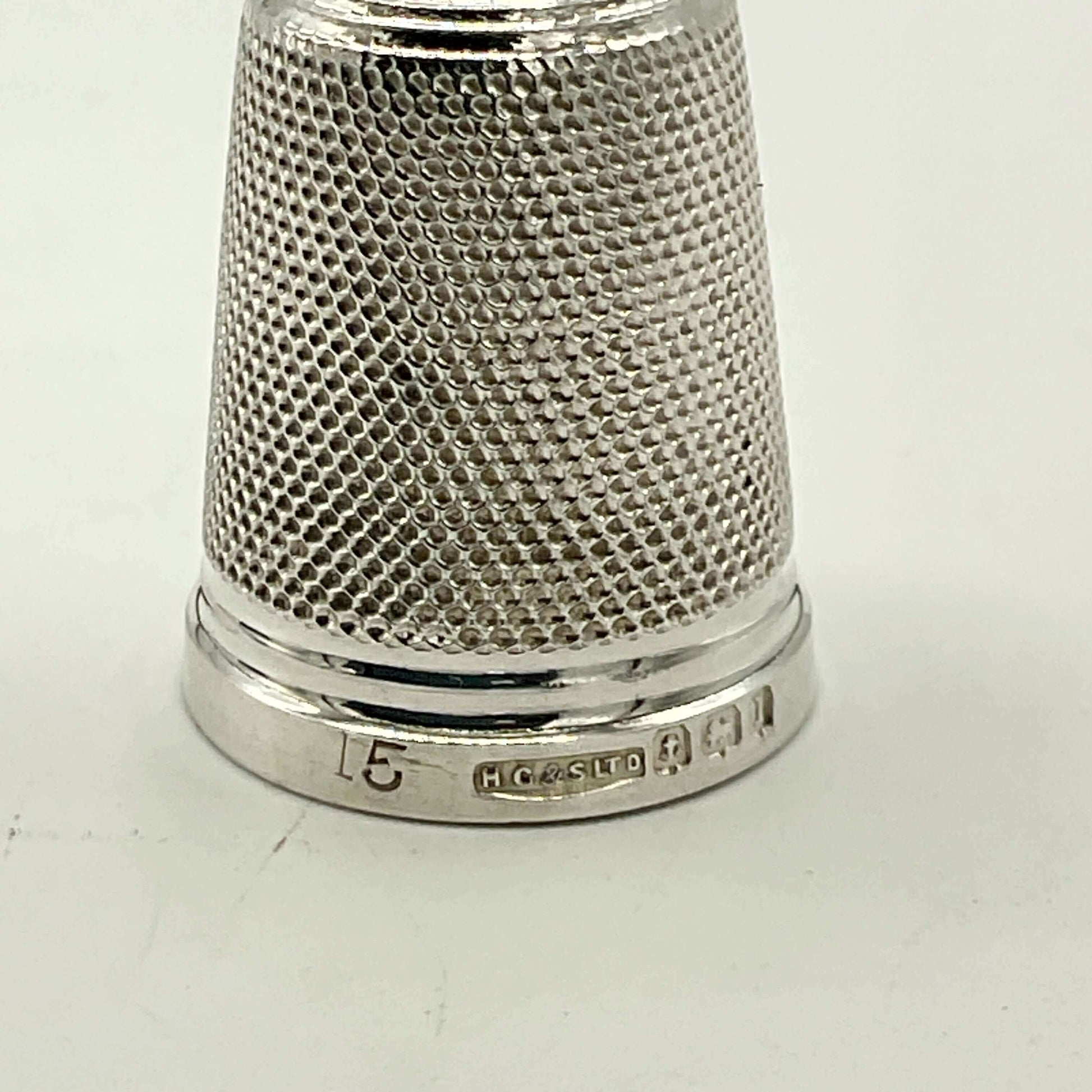 Silver thimble with textured surface on a white background