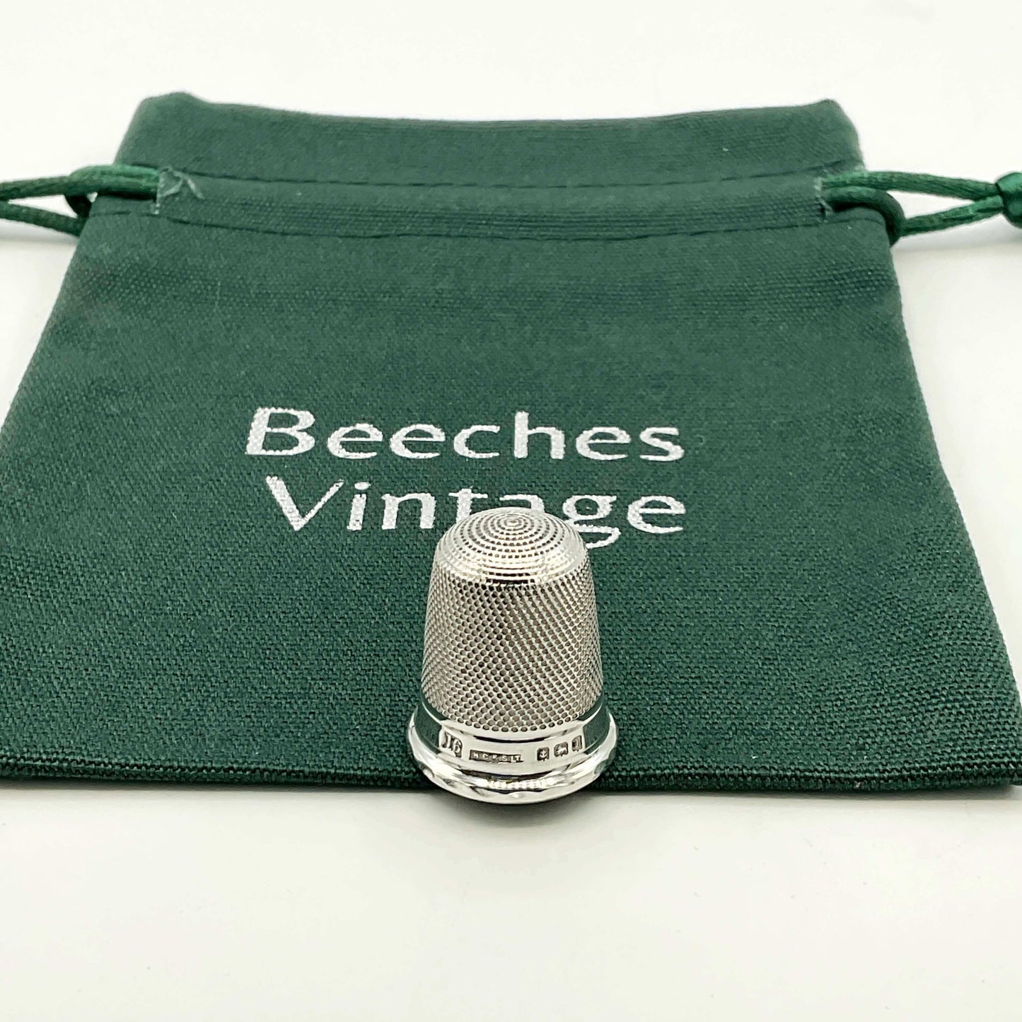 Silver thimble on a green drawstring bag with 'Beeches Vintage' text.