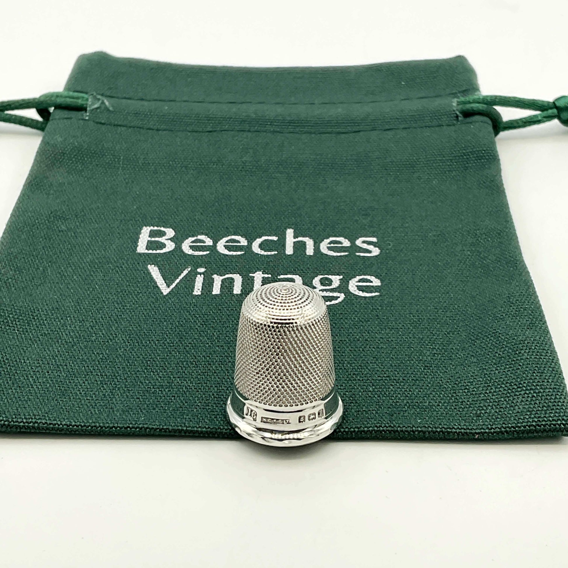 Silver thimble on a green drawstring bag with 'Beeches Vintage' text.