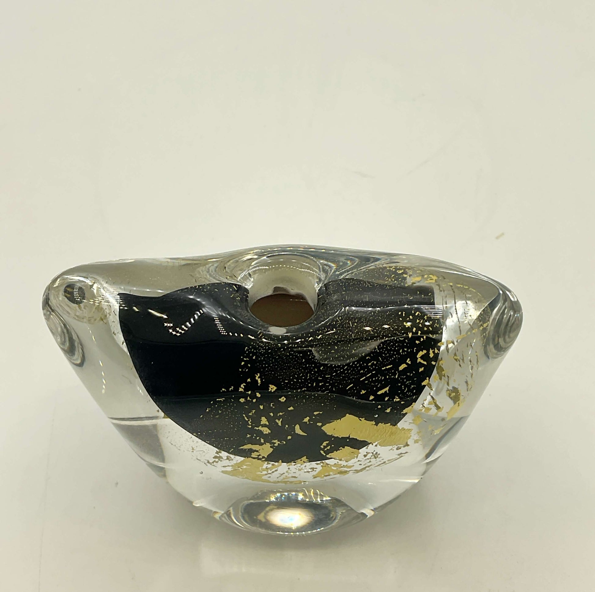 A clear glass decorative vase with a black interior and scattered gold flecks, photographed on a plain light background.