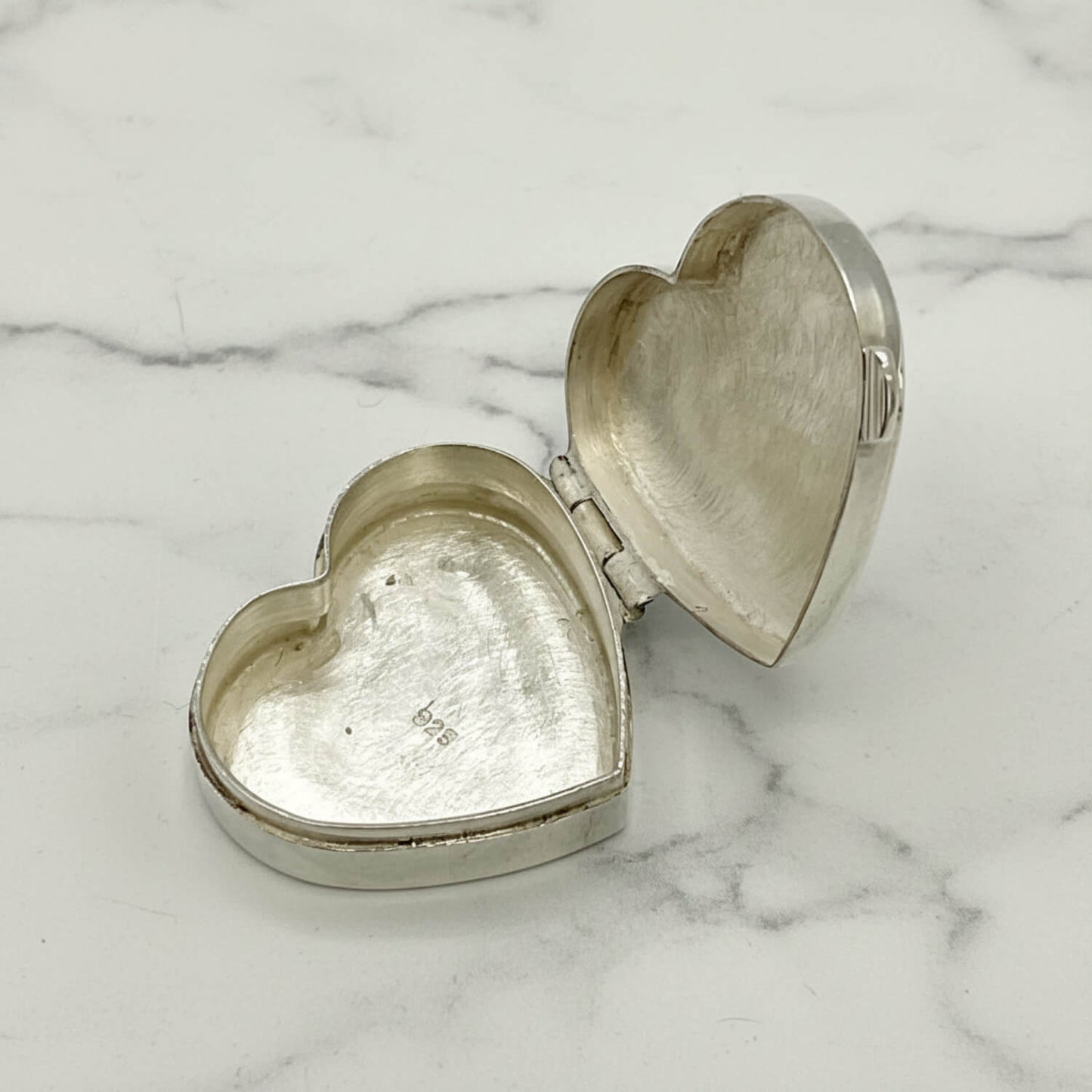 Heart-shaped silver trinket pill box on a marble surface