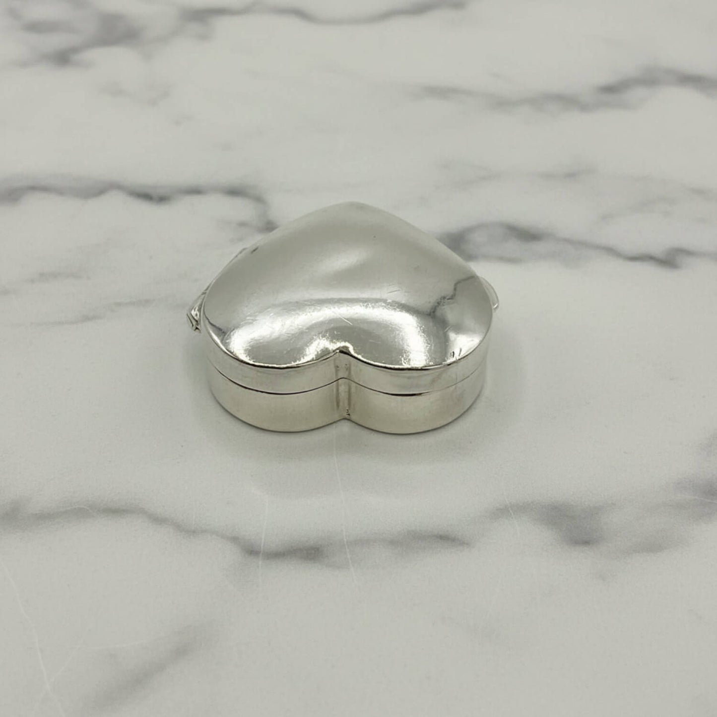 Heart-shaped silver trinket box on a marble surface