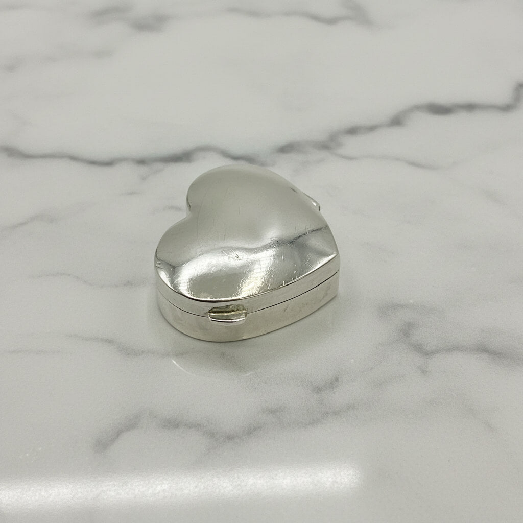 Silver heart-shaped box on a white marble background