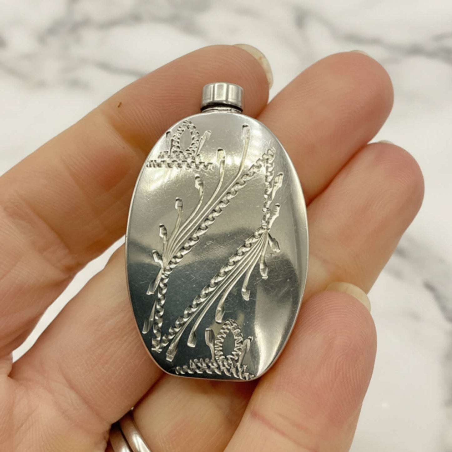 Small Sterling Silver Scent Bottle held in a hand against a neutral background