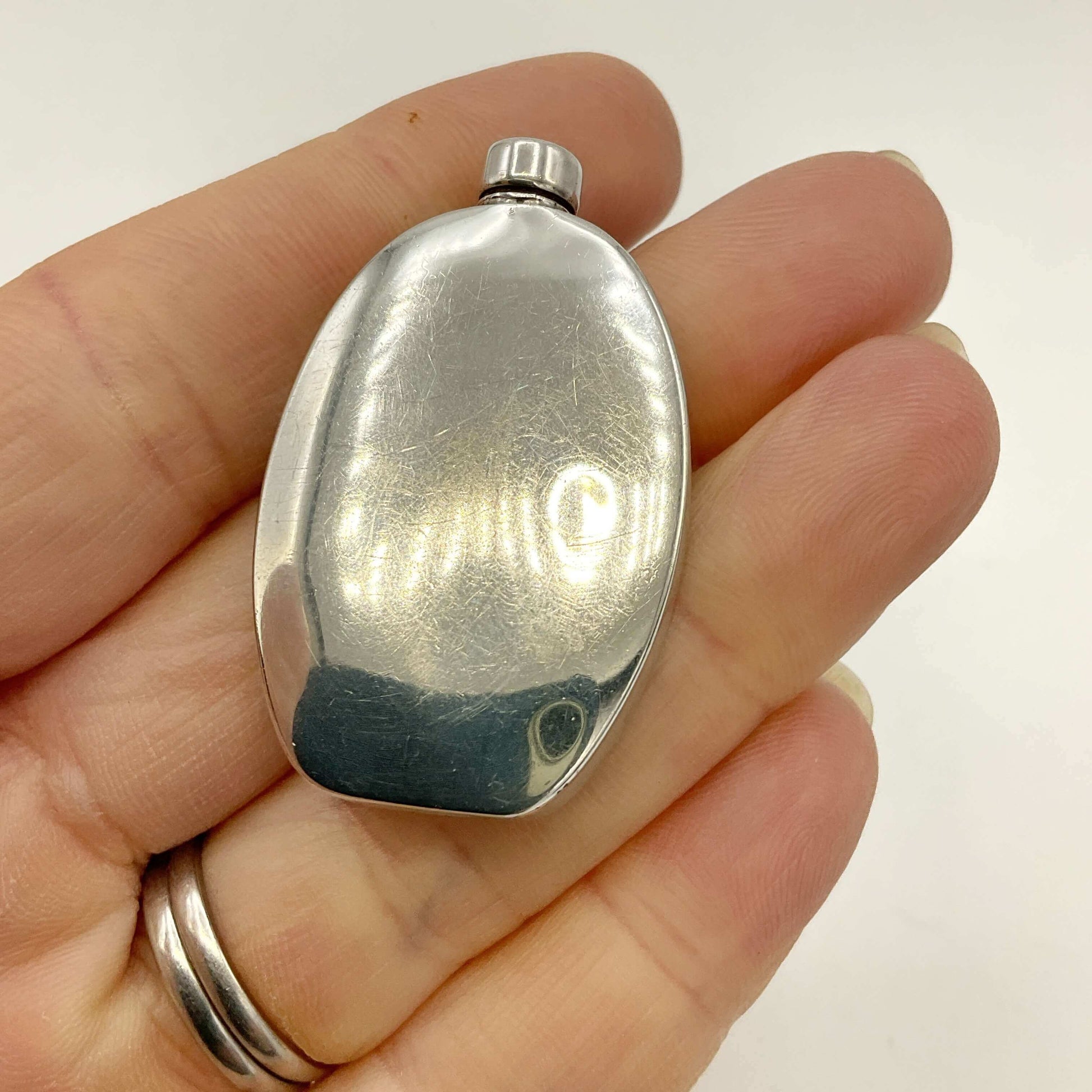 Small Sterling Silver Scent Bottle held in a hand against a white background