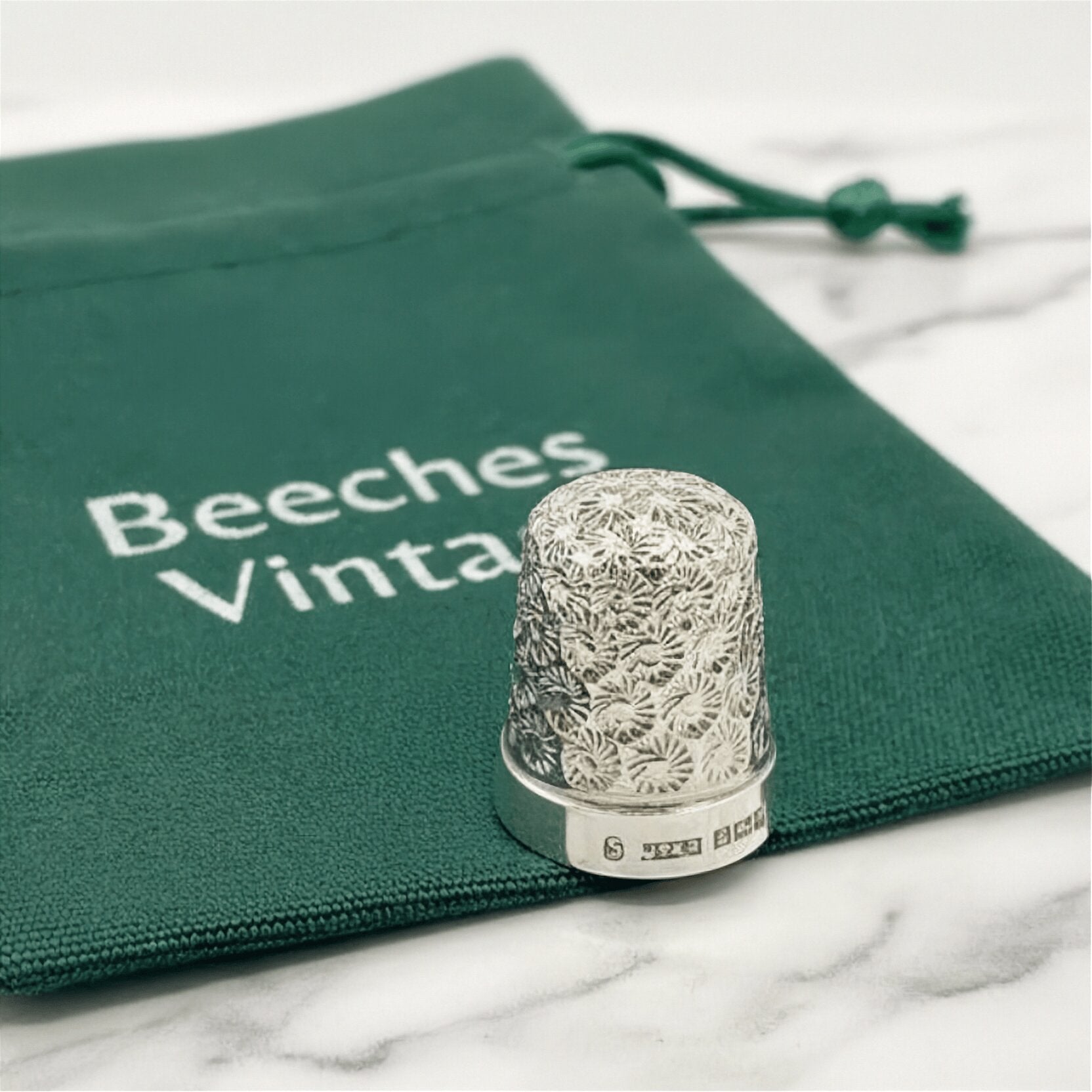 Silver thimble on a green drawstring bag with 'Beeches Vintage' branding.