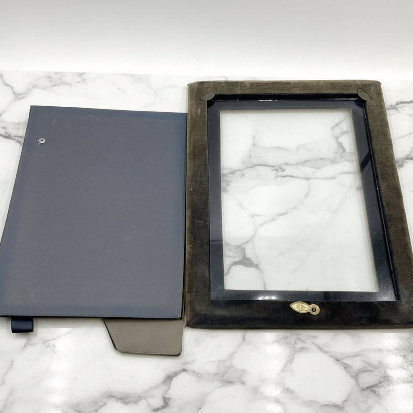 Back of black rectangular frame with glass on a marble surface