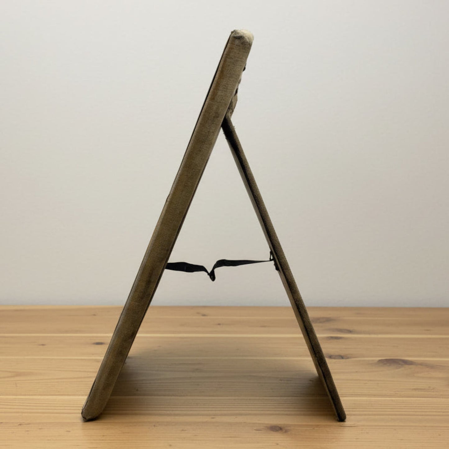 side view of photo frame stand on a wooden surface with a plain background