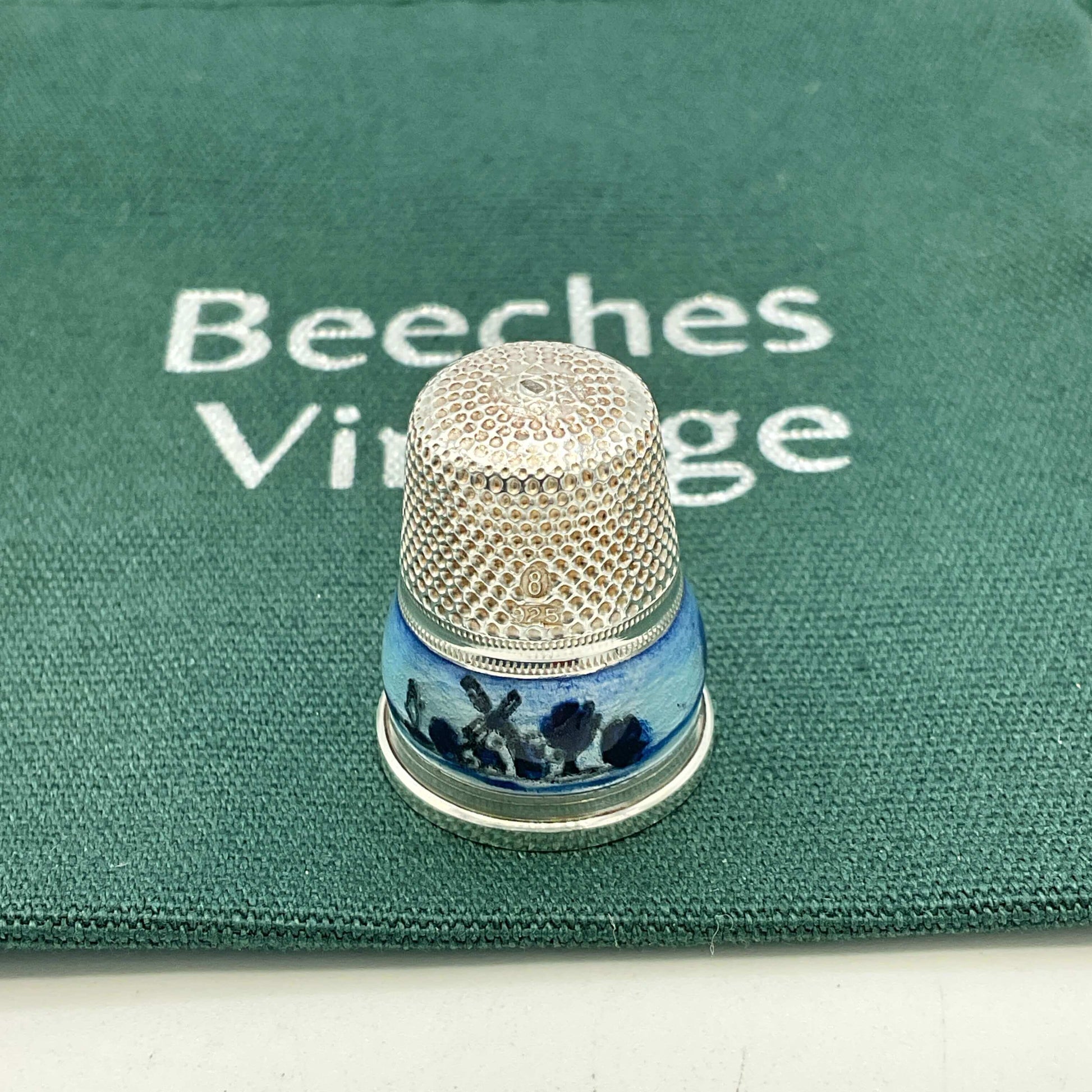 Decorative thimble with blue windmill design on a green fabric bag background with 'Beeches Vintage' branding.