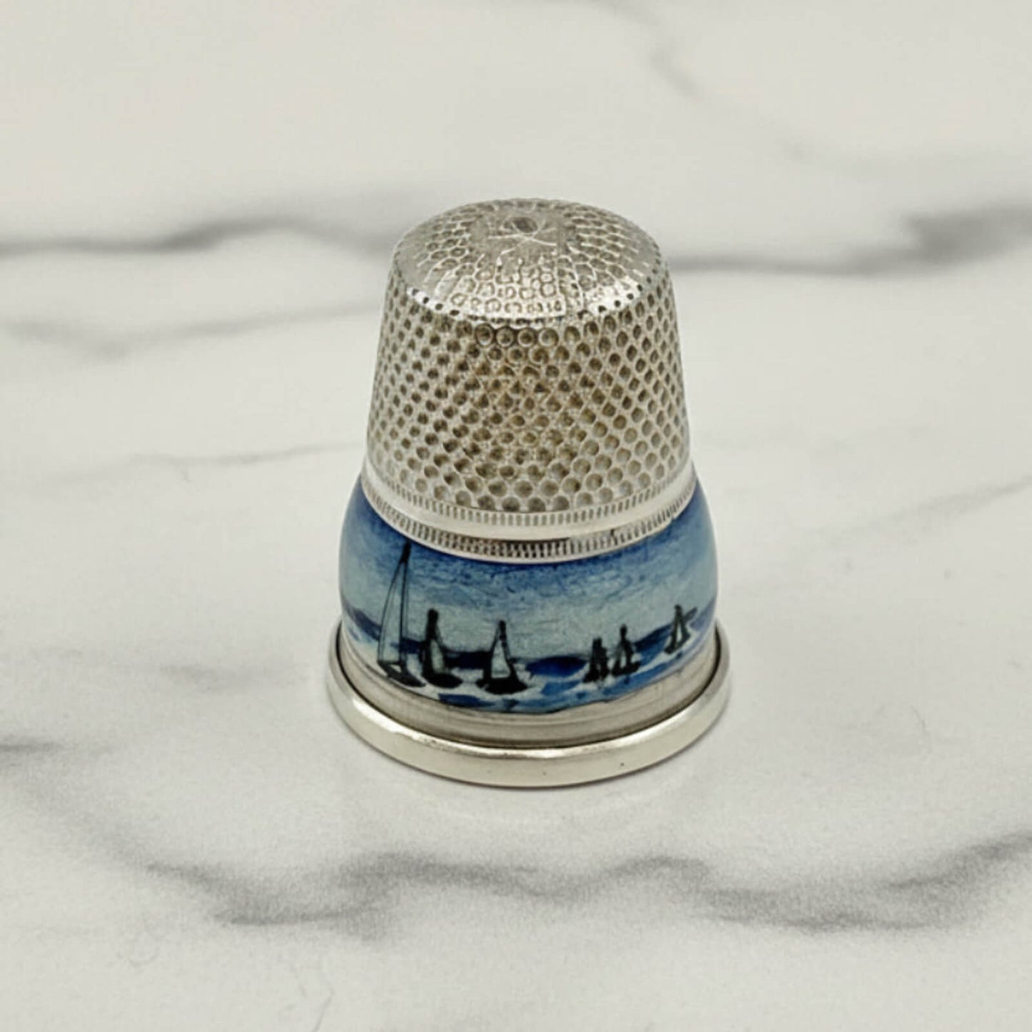 Silver Thimble with a blue boat enamel on a marble background