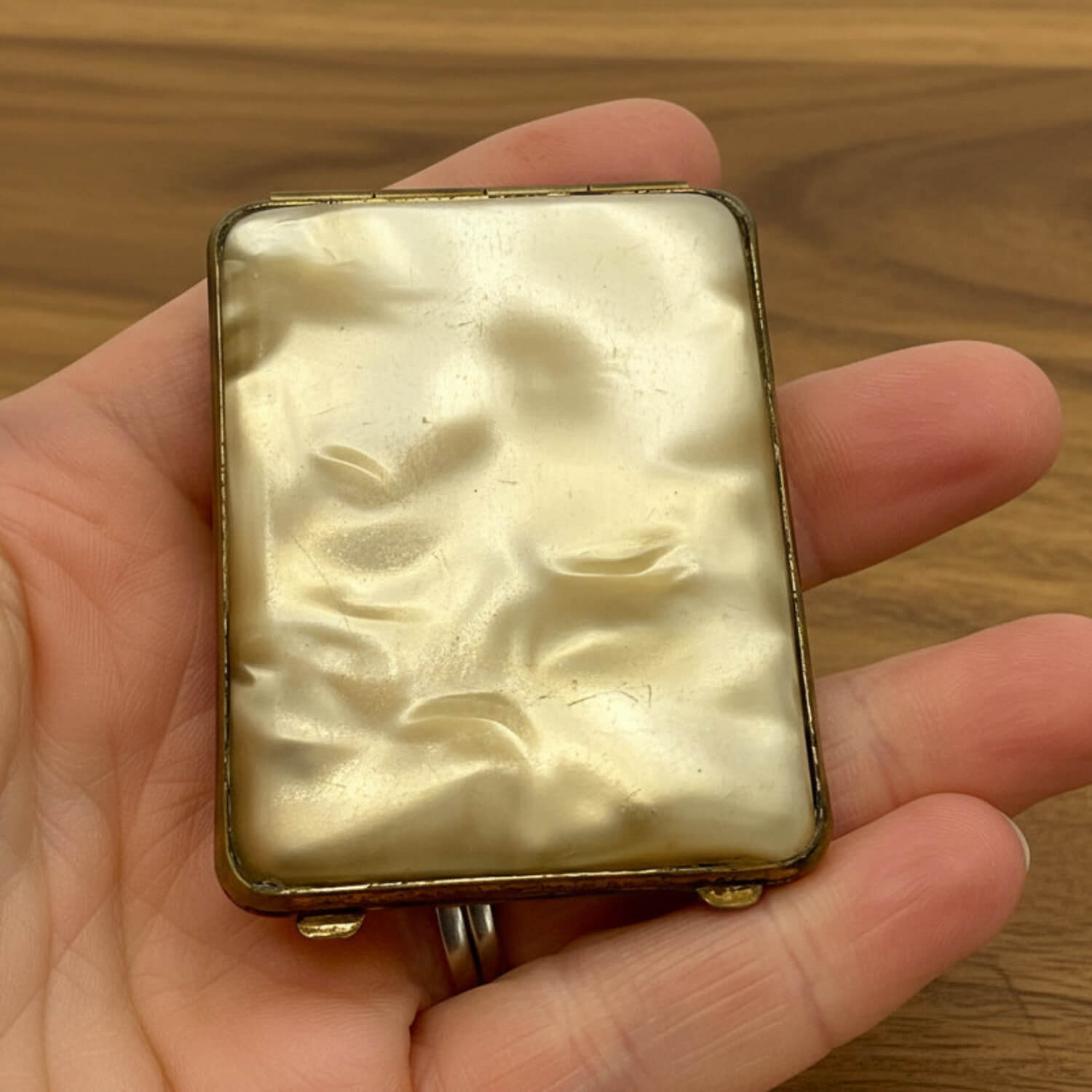 cream case held in a hand with a wooden background