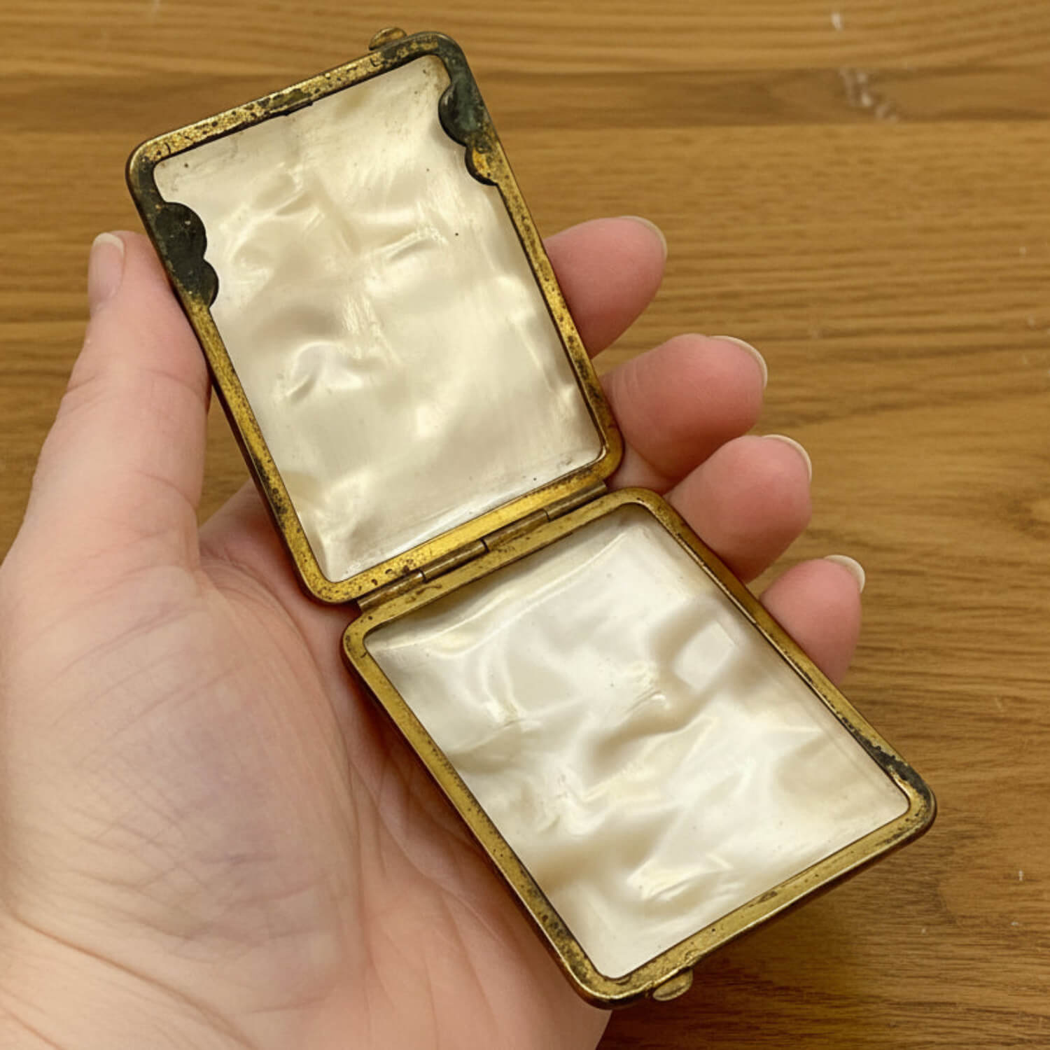 Hand holding an open small case on a wooden surface