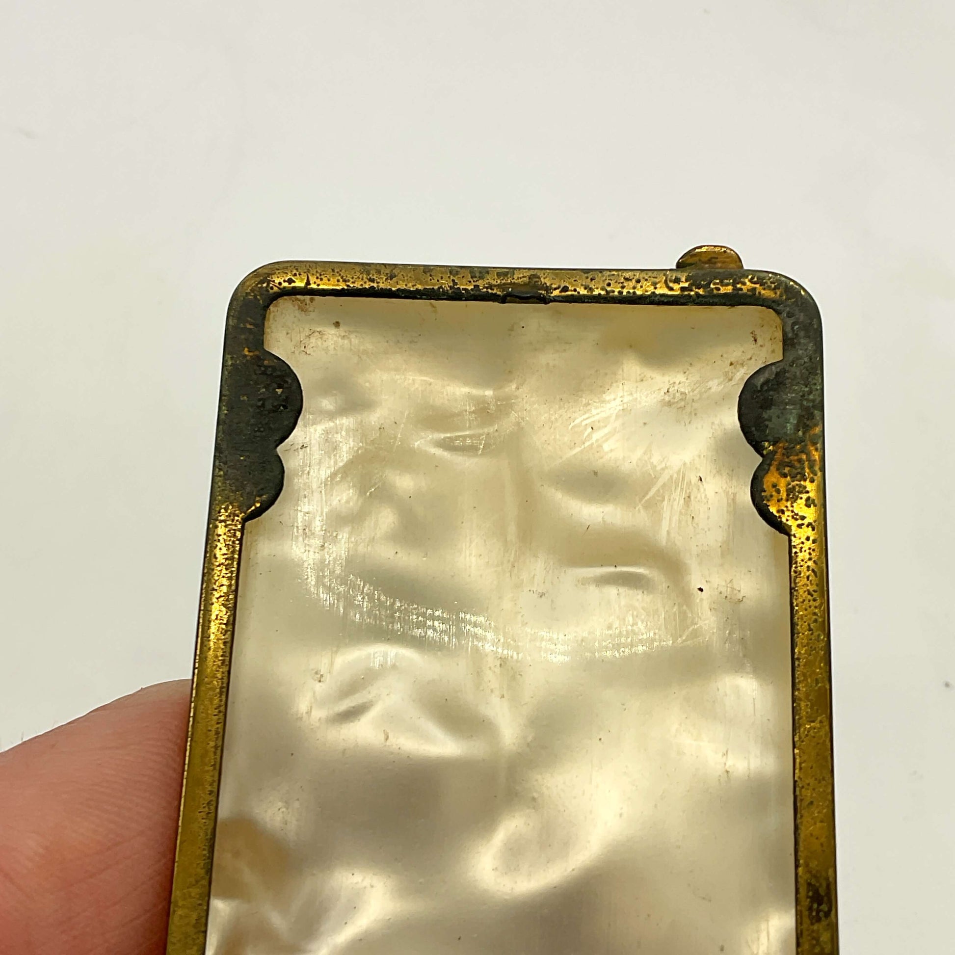Rectangular case with brass frame held by a hand on a white background