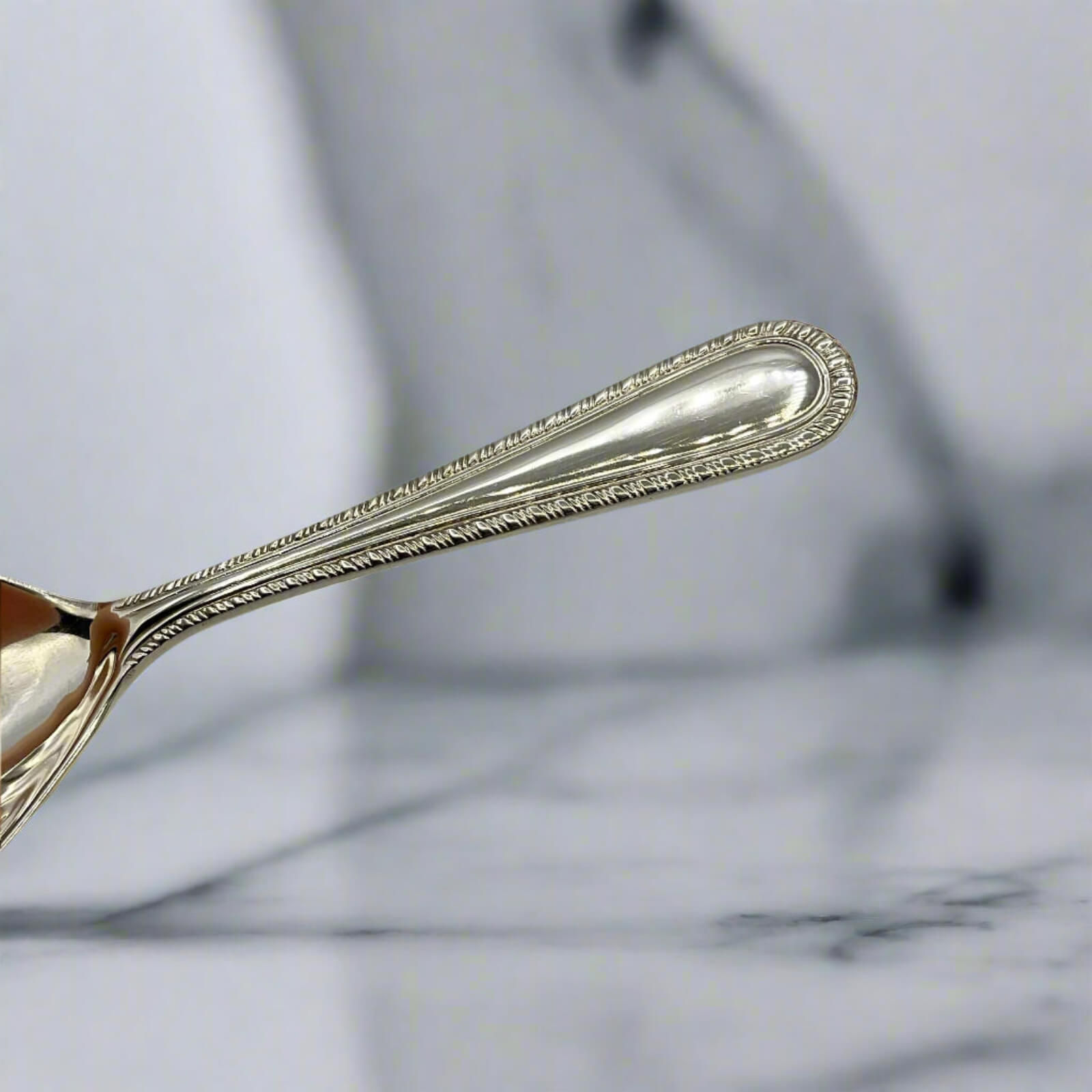 Close-up of a silver spoon handle on a marble surface