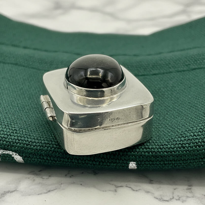 side view of Vintage Black Gemstone Silver Pill Box on green bag
