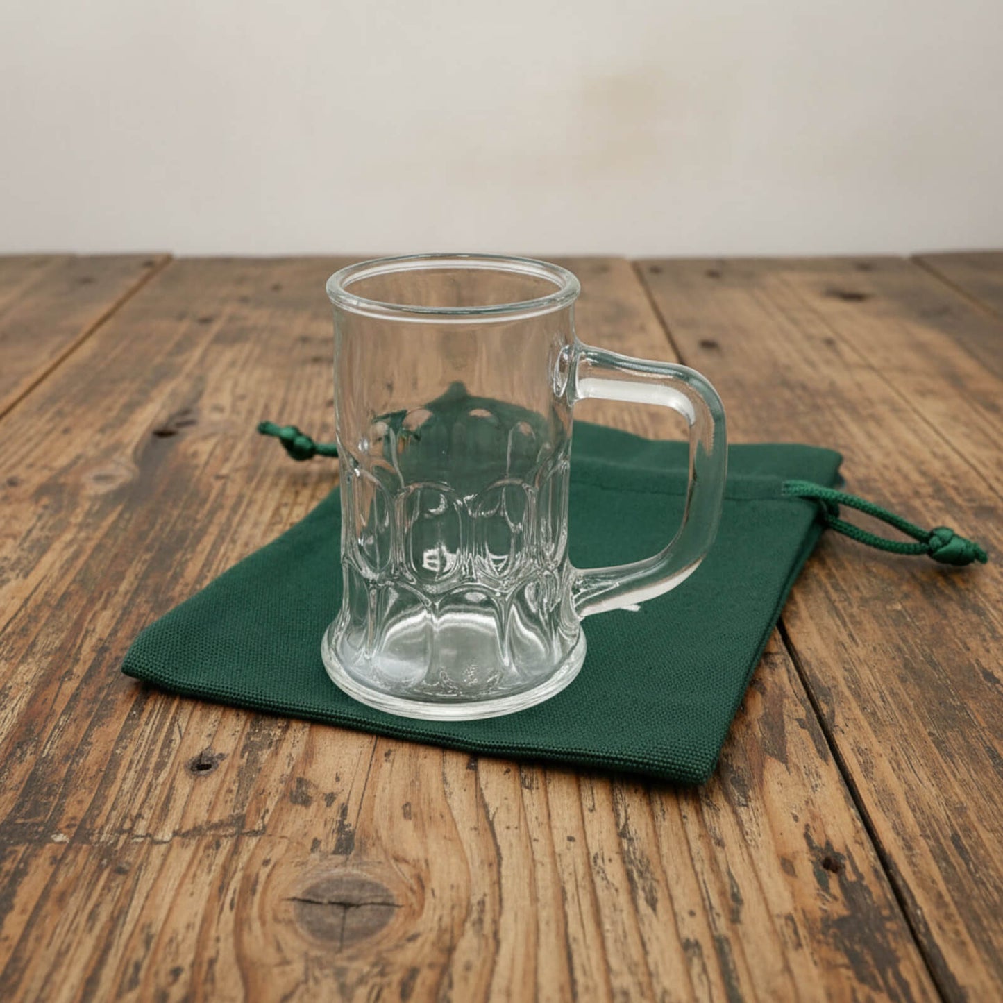 Clear glass mug on a green cloth with a wooden background