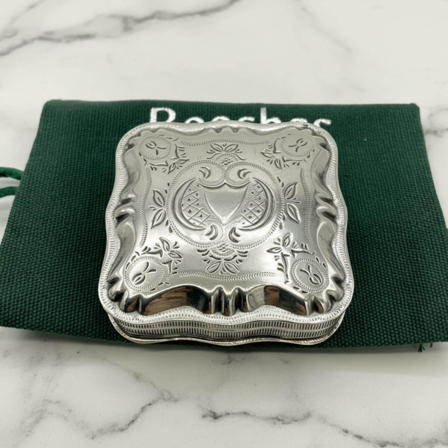Vintage Small Dutch Silver Box On a green bag on a marble surface 