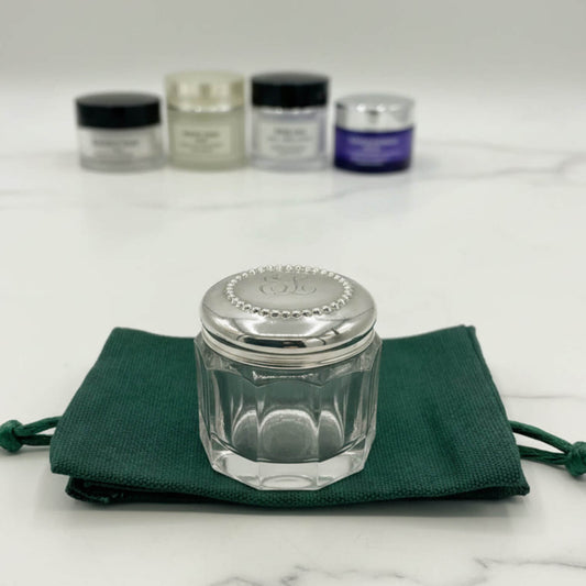 Clear glass jar with silver lid on a green cloth, with other similar jars in the background.