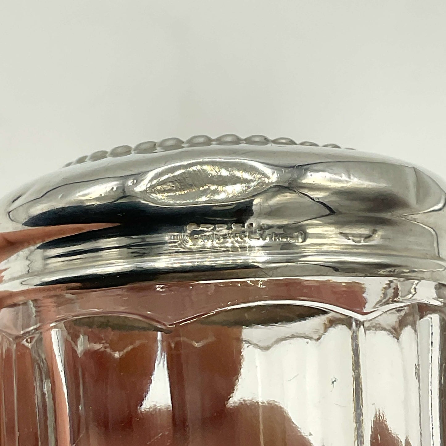 Close-up of a silver lid on a glass jar with a white background